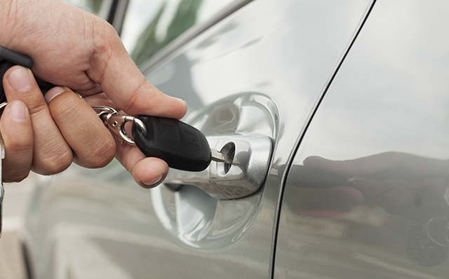 Kraftfahrtversicherung: Eine Hand schließt eine PKW-Tür auf.