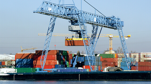 Ein großer Kran belädt einen Container auf ein Schiff.