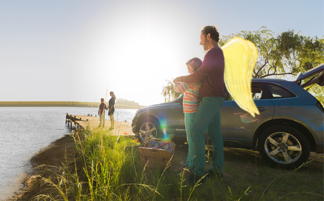 Kraftfahrtversicherung: Ein Vater mit Schutzengel-Flügeln steht mit seinem Kind am See. Im Hintergrund das parkende Auto.